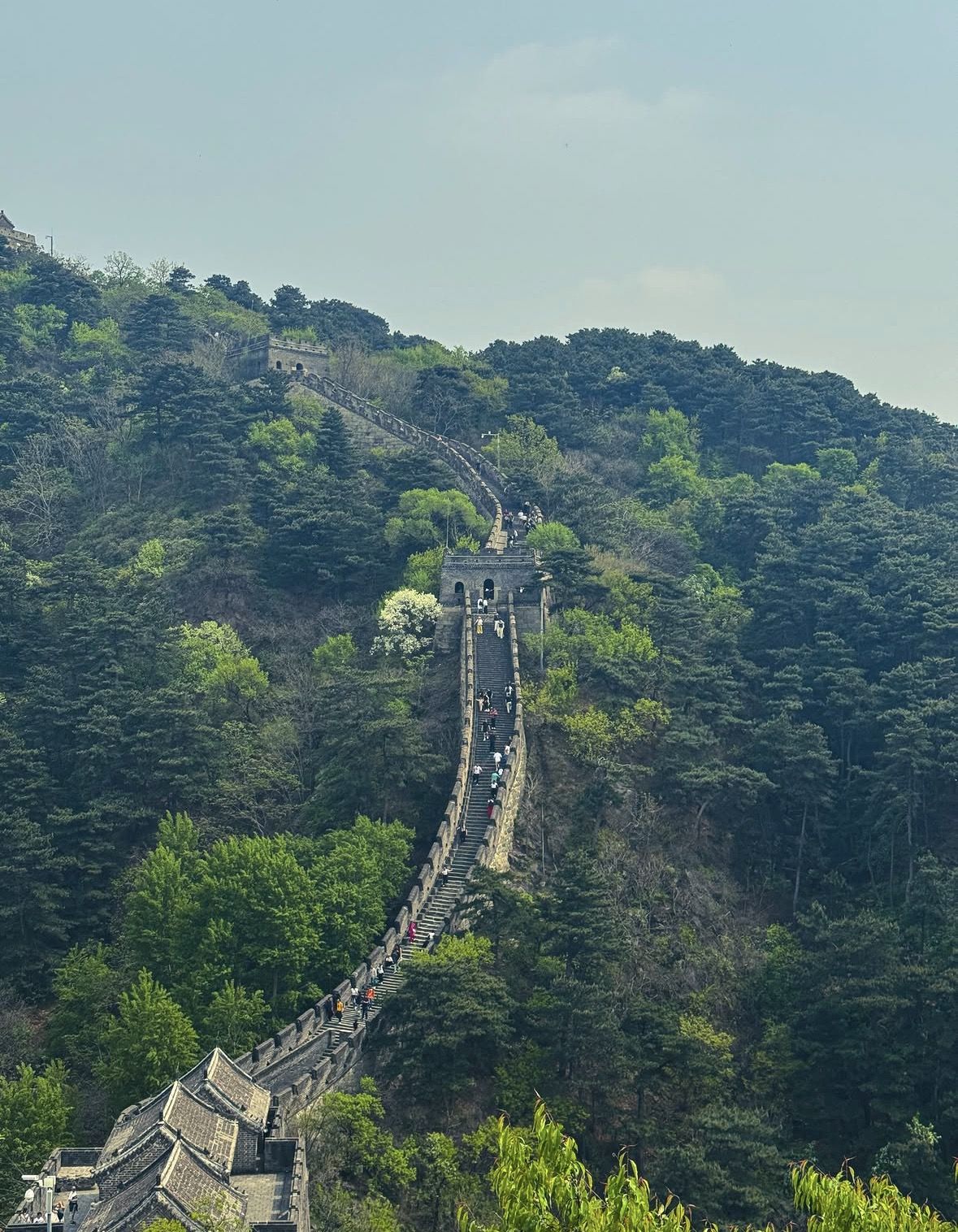 Tour bus parked at the base of the Great Wall of China with mountains visible in the background